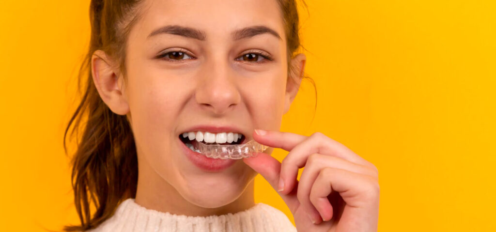 teen girl holds aligner and learns Invisalign process step by step