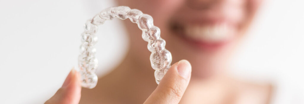 adult holds aligners after learning Invisalign tips